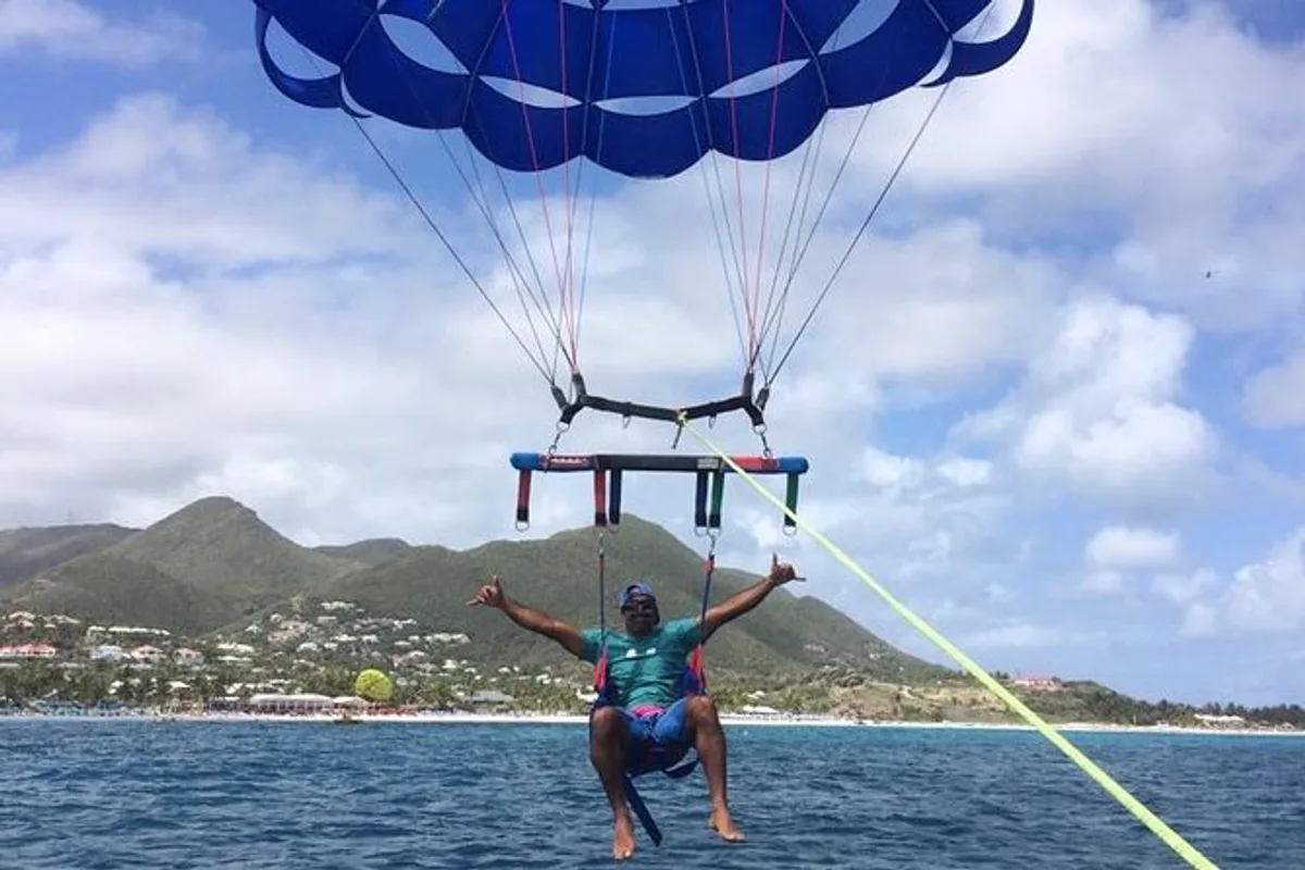 Two riders gliding high above the turquoise sea while parasailing in St Maarten near Orient Bay Beach